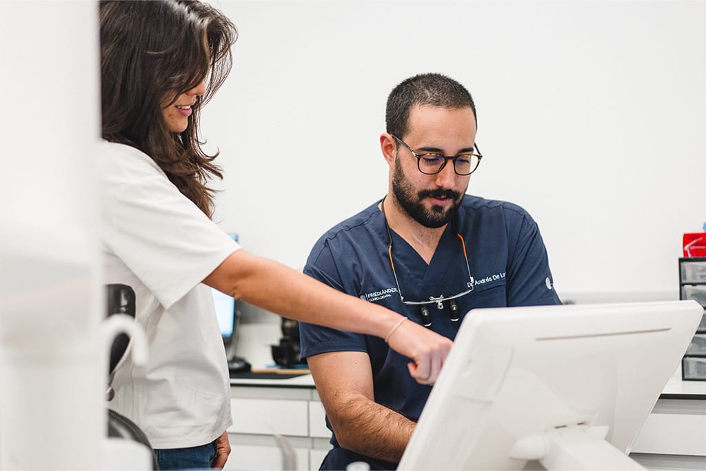 Prótesis dental Barcelona: dentista muestra a su equipo el plan de tratamiento del paciente en la pantalla