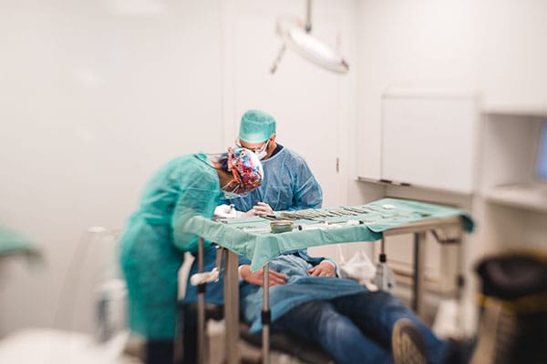 Cirugía Oral: Apicectomía con equipo quirúrgico trabajando sobre paciente