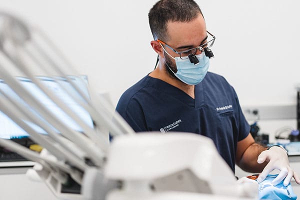 Dentista con lupas ajustando una prótesis removible en boca del paciente